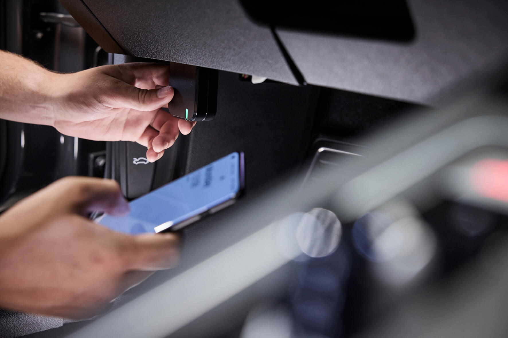 Hands plugging autotuner one into a car obd port